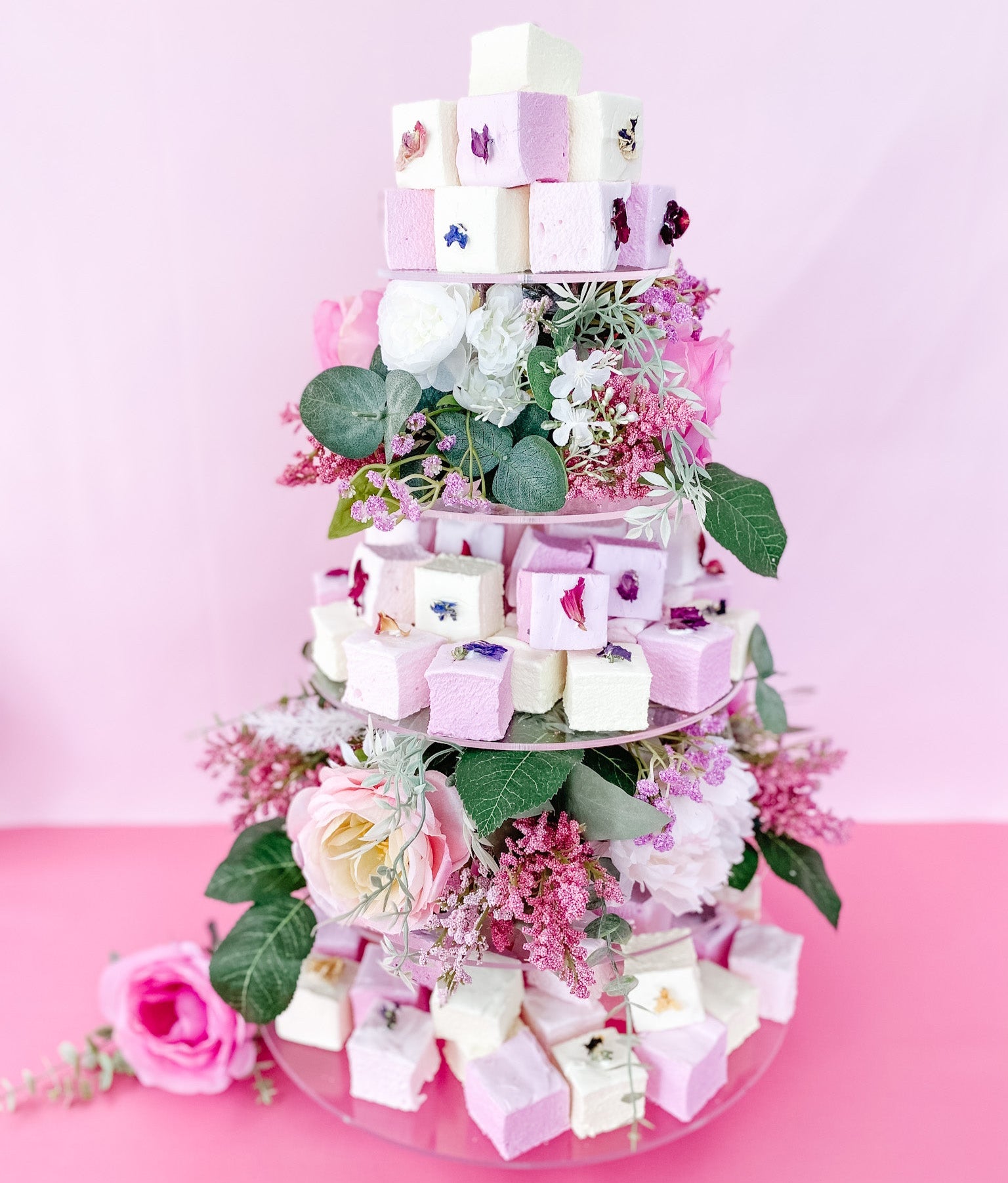 Decorative tiered gourmet marshmallows with  flowers on a pink background
