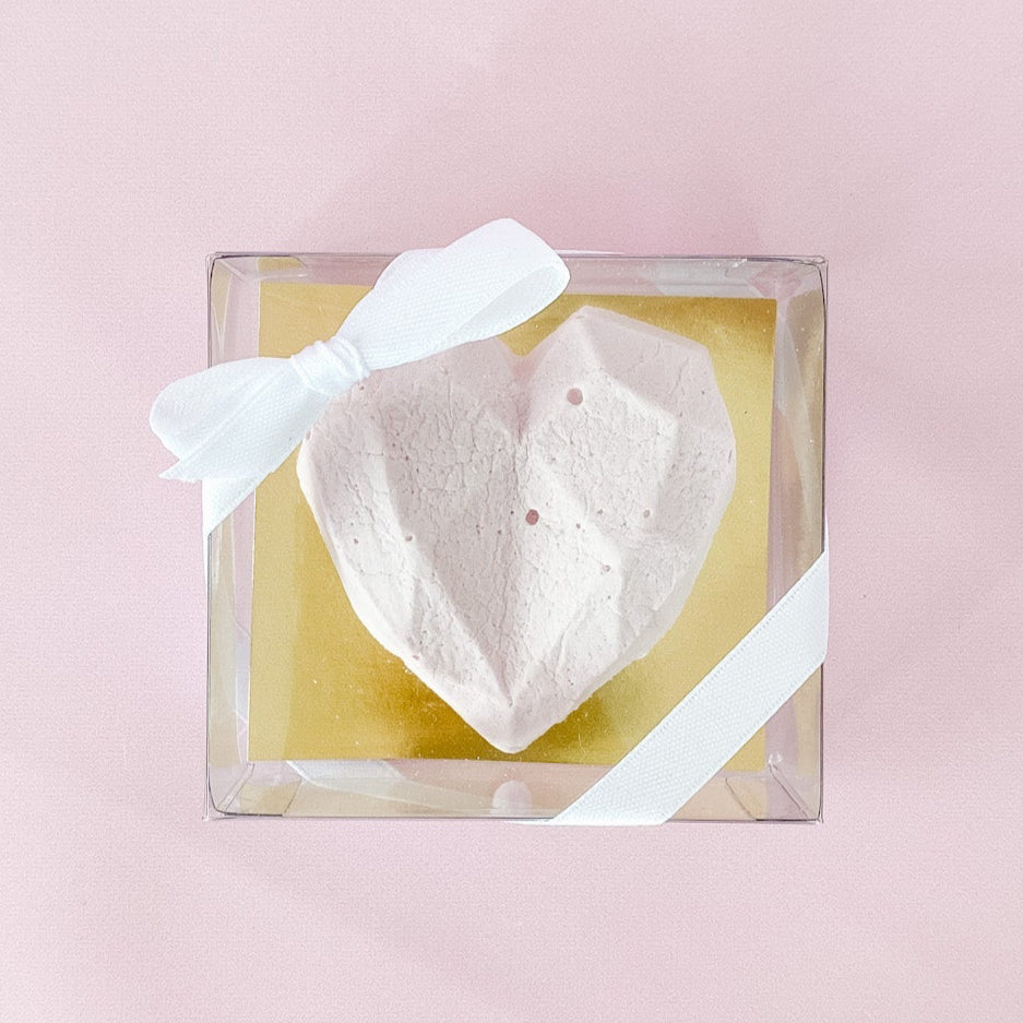 Heart-shaped gourmet marshmallow with a white bow in a clear box on a pink background